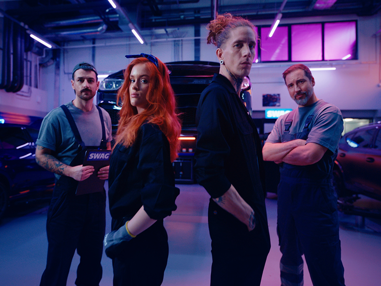 Three male mechanics and one female mechanic posing in a workshop
